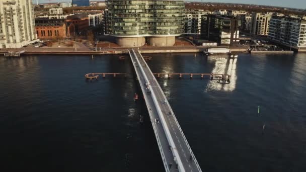 Mensen bij de fietsbrug met oude en moderne gebouwen eromheen — Stockvideo