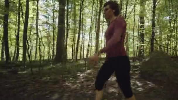 Mujer con Leggins Negros Caminando Rápido con una Vista de los Árboles Forestales en el Fondo — Vídeos de Stock