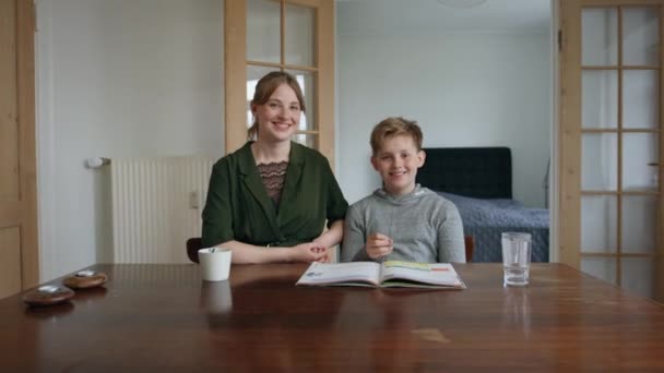Krásná fotka mladšího bratra a starší sestry a syna usmívající se s otevřenou učebnicí vpředu — Stock video