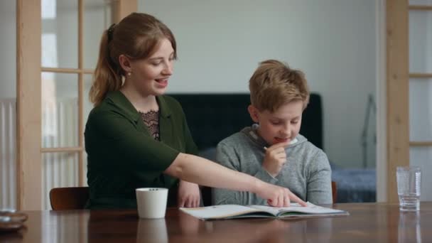 Menino escreve respostas em seu livro com sua irmã guiando-o — Vídeo de Stock