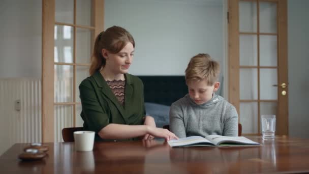 Äldre syrran hemundervisar sin lillebror när hon vägleder honom med sitt kalkylblad — Stockvideo