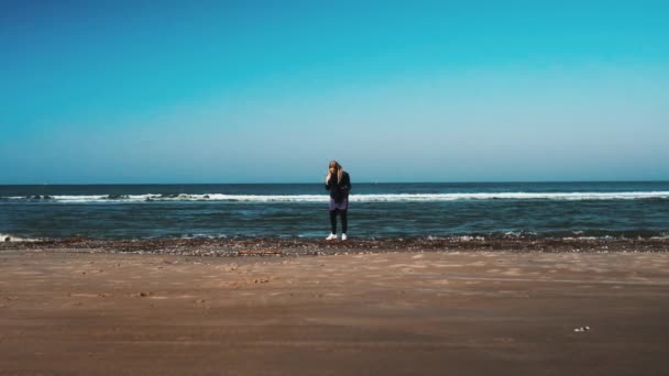在一个阳光灿烂的日子里站在丹麦沙滩上的一名妇女被枪杀 — 图库视频影像
