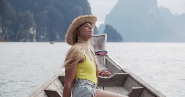 Женщина-путешественница на лодке у озера с ветром, мягко дующим ее волосы — стоковое видео