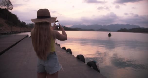 Žena Turistka u doků Fotografování jezera se svým telefonem — Stock video