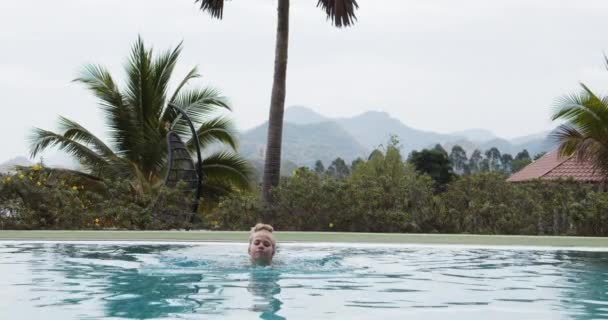 Blonde Frau schwimmt im Freien mit schönem Blick auf die Berge — Stockvideo