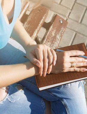 Eli kalem not defterinde yazıyor.