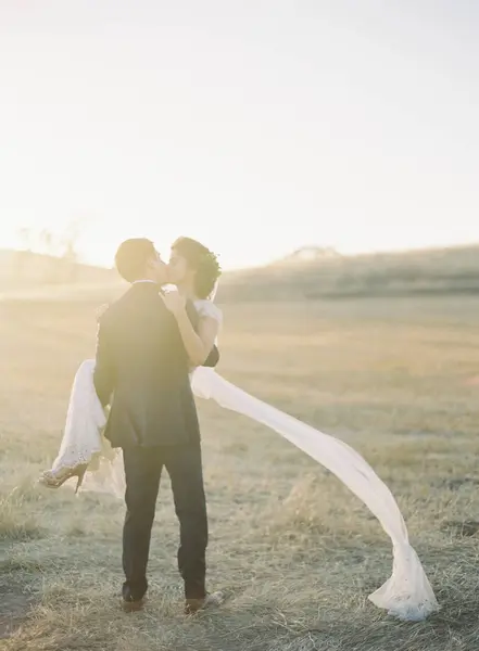 Noivo segurando e beijando noiva — Fotografia de Stock