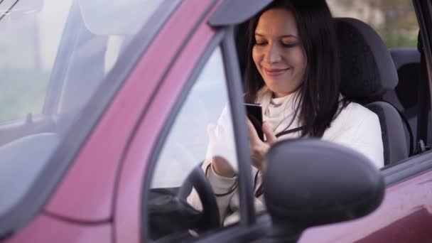 Kobieta rozmawia na smartfonie, siedząc w samochodzie — Wideo stockowe