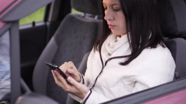 Kadın arabada oturan bir smartphone cep telefonu ile bir ileti yazar