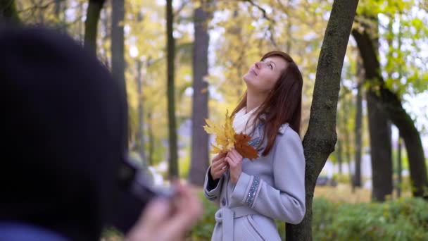 Fotógrafo tira uma foto de uma jovem mulher ao ar livre — Vídeo de Stock