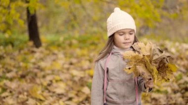 Sonbahar yapraklarıyla oynayan kız