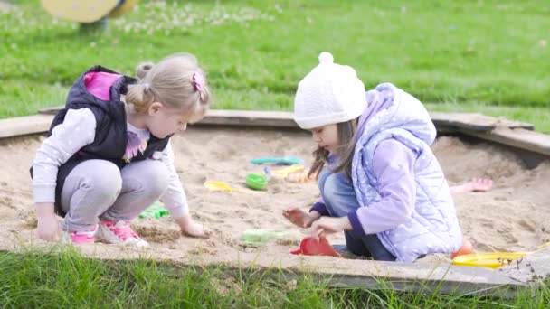 Duas meninas brincam na caixa de areia — Vídeo de Stock