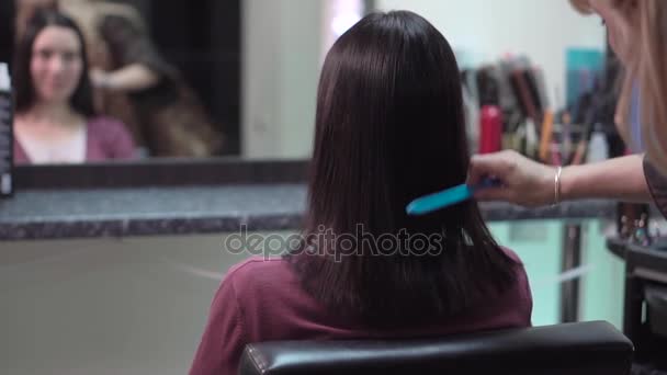Перукар розчісує волосся в салоні краси — стокове відео