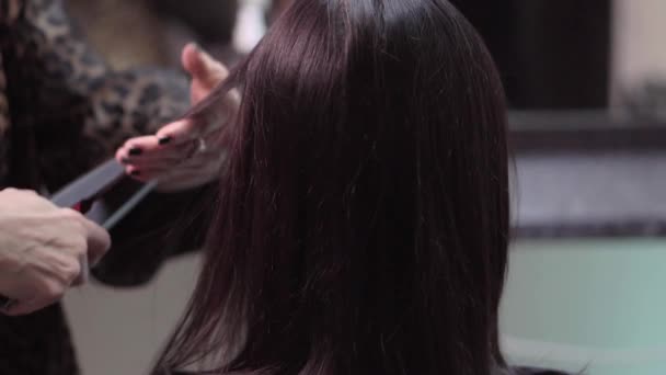 Fodrász egy női ügyfél használata fűtött haj Egyenesítő hosszú fekete haj hajkiegyenesítő
