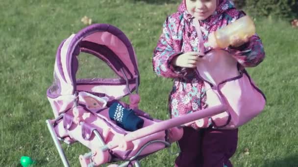 Kind voeding haar pop met speelgoed fles — Stockvideo