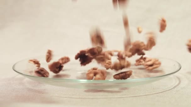 Núcleos secos de nuez cruda que caen en un recipiente de vidrio — Vídeos de Stock