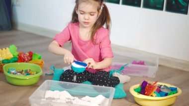 Sevimli küçük bir kız evde Kinetik kumla oynayan