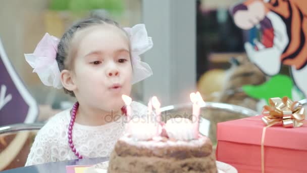 Menina soprando velas no bolo de aniversário — Vídeo de Stock