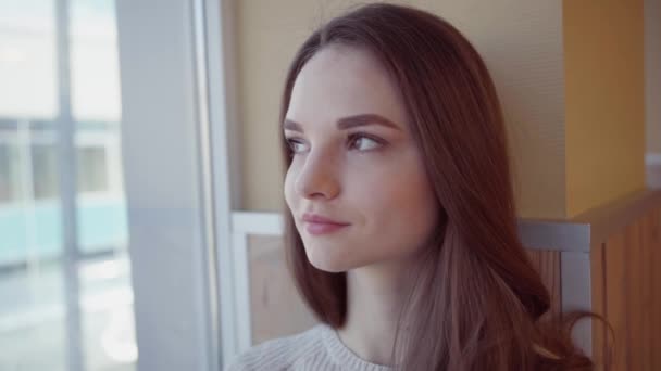 Mujer joven está mirando por la ventana — Vídeo de stock