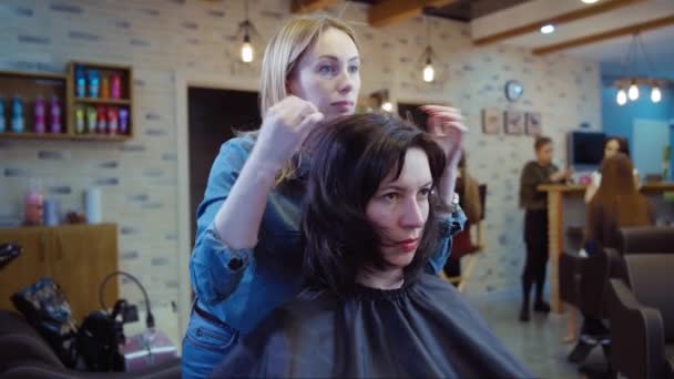 Mujer consiguiendo nuevo corte de pelo por peluquería en el salón — Vídeo de stock