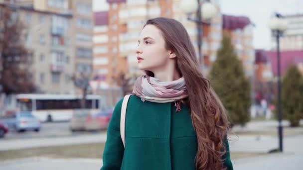 Joven morena de pelo largo con abrigo en una calle de la ciudad — Vídeos de Stock