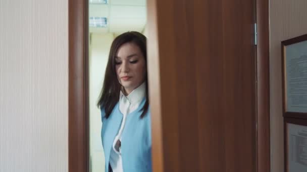 Empresária morena em um casaco azul abre a porta e entra em seu escritório . — Vídeo de Stock