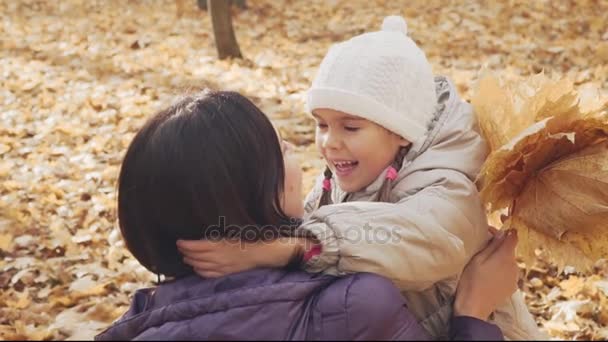 Lycklig liten flicka kramar hennes mamma i höst park. — Stockvideo