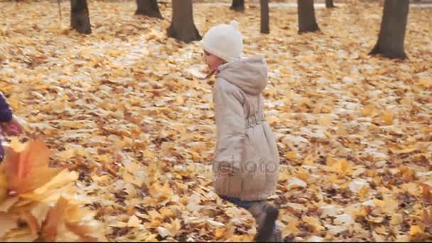 Niña feliz jugando con su madre en el parque de otoño . — Vídeo de stock