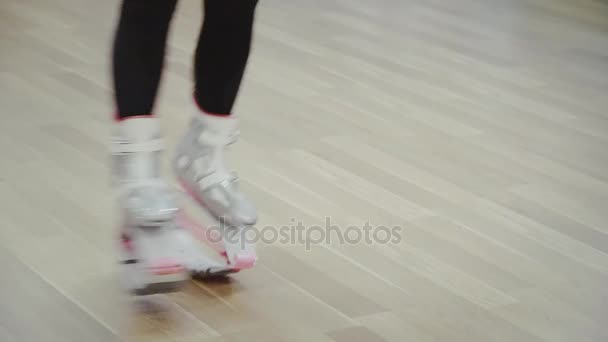 Rubia bonita mujer joven saltando en zapatos de kangoo en el gimnasio . — Vídeos de Stock