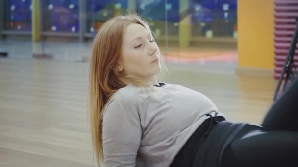 Блондинка красива молода жінка лежить і робить розщеплення в тренажерному залі . — стокове відео