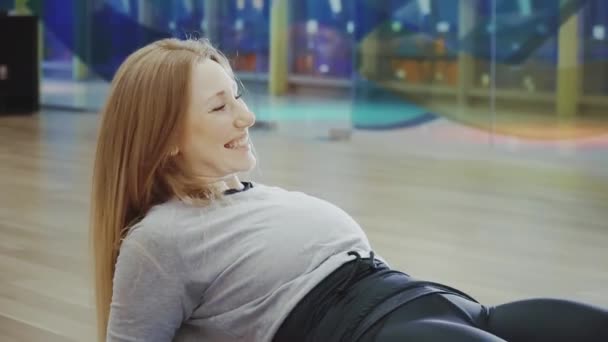 Joyeux blonde jolie jeune femme couchée et faisant des fentes dans la salle de gym . — Video