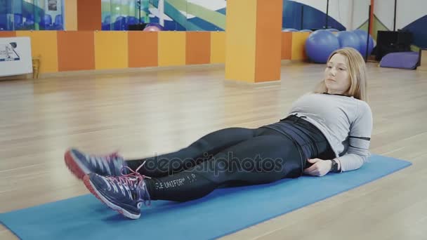 Rubia bonita mujer joven mintiendo y haciendo splits en el gimnasio . — Vídeo de stock