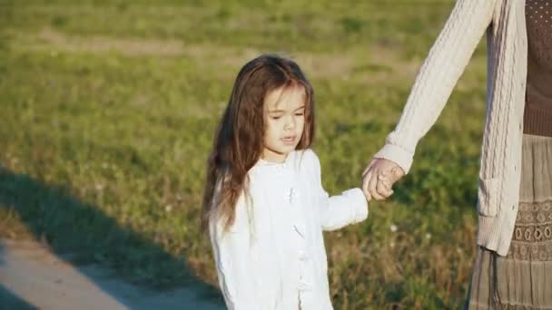 Niña con su mamá caminando por el camino rural al atardecer . — Vídeos de Stock