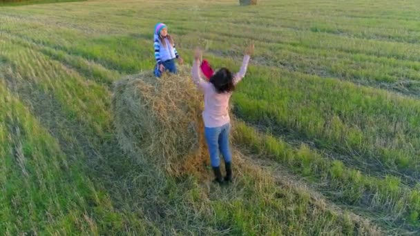 Little girl sits on the stack and throw straws to her mom. — Stock Video