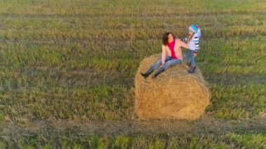 Anne ile kızı günbatımında rustik alan saman yığınında oturmak.