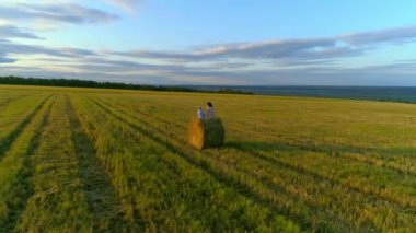 Anne ile kızı günbatımında rustik alan saman yığınında oturmak.