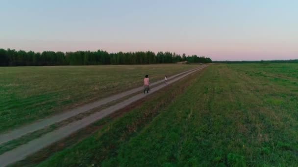 Mãe com filha correr na estrada rural ao pôr do sol . — Vídeo de Stock