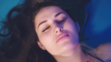Güzel kız sakin ol. Mavi suda gözlerini kapar. Spa havuzu banyosu yapar. Doldur..