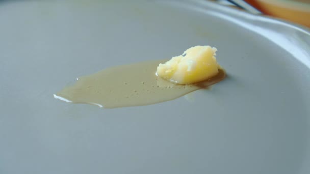 Yellow ghee butter moves and melts on a hot gray frying pan grey. Slowmo. — Stock Video