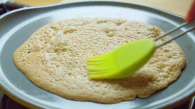 Mutfaktaki sıcak tava gazı sobasının üzerine tereyağlı fırça sürülmüş krep. Yavaş yavaş yakınlaş.