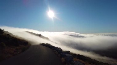 Portekiz 'deki Madeira adasındaki dağların üzerinden geçen beyaz bulutların 4k videosu. Güneş doğuyor. Uçan bulutların manzarası manzarayı kaplıyor ve batıyor.