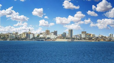 Afrika 'nın Senegal başkenti Dakar' ın manzarası. Bir tekneden alınmış bir şehir manzarası. Büyük modern binalar ve bulutlu mavi bir gökyüzü var..