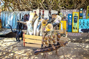Dakar, Senegal 22 Nisan 2019, tipik Senegal çizimleriyle boyanmış inek boynuzlarından güzel kaplar. Bu Afrika 'da yerel bir sanattır. Teknedeki ahşap heykelcikler..