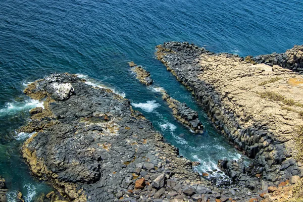 Θάλασσα γκρεμό με μαύρες πέτρες στο νησί Goree, κοντά στο Ντακάρ, Σενεγάλη. Υπάρχει το τυρκουάζ νερό του Ατλαντικού Ωκεανού τυπικό της Αφρικής. Είναι μια όμορφη ηλιόλουστη μέρα.. — Φωτογραφία Αρχείου