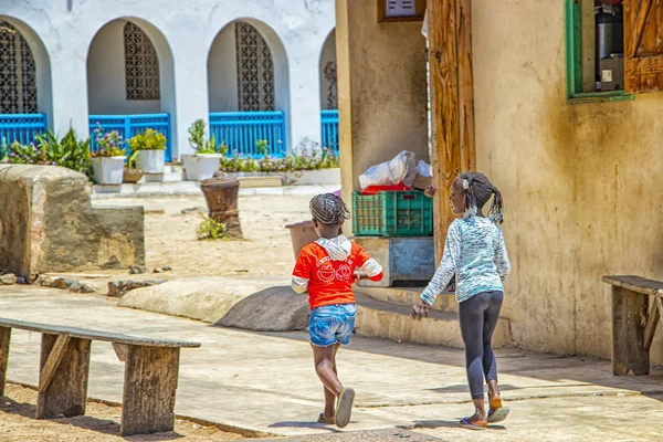 Isla Goree, Senegal- 22 de abril de 2019: Chicas no identificadas caminan por una calle arenosa en una pequeña ciudad. — Foto de Stock