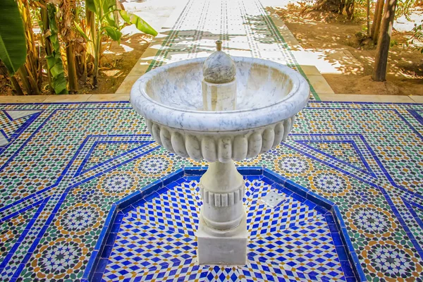 Fehér kő szökőkút közepén zöld kert iszlám palota. Marokkóban van. A szökőkút áll a kék-fehér csempe tipikus arab és Berber díszek — Stock Fotó
