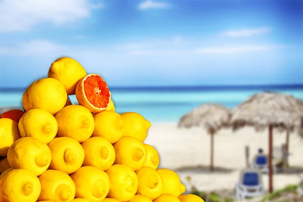 Grandes limões na praia na ilha do Caribe. Frutas tropicais amarelas O fundo é desfocado. Há mar claro e praia arenosa. — Fotografia de Stock