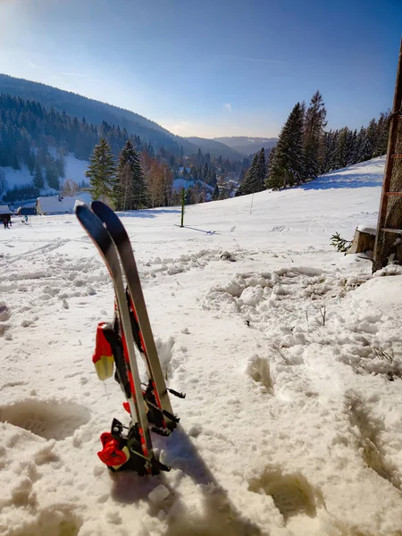 Τα σκι στέκονται στο χιόνι και αγναντεύουν την πλαγιά του σκι και τον γαλάζιο ουρανό. Είναι μικρά παιδικά πέδιλα σκι. Είναι στα βουνά Ore, Τσεχική Δημοκρατία. — Φωτογραφία Αρχείου