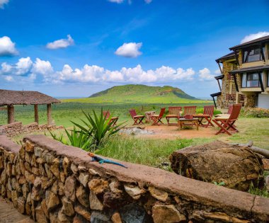 Şömine ve ahşap sandalyeler. Arka planda Kenya 'daki Tsavo Doğu Ulusal Parkı' nın harika bir manzarası var..