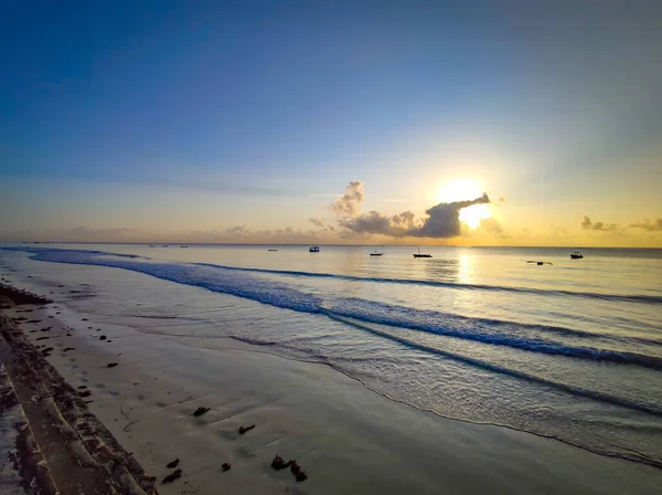 Hermoso amanecer en la playa de Diani en el Océano Índico. Es una mañana soleada en Kenia, África. Hay pequeños barcos de madera en el agua . — Foto de Stock